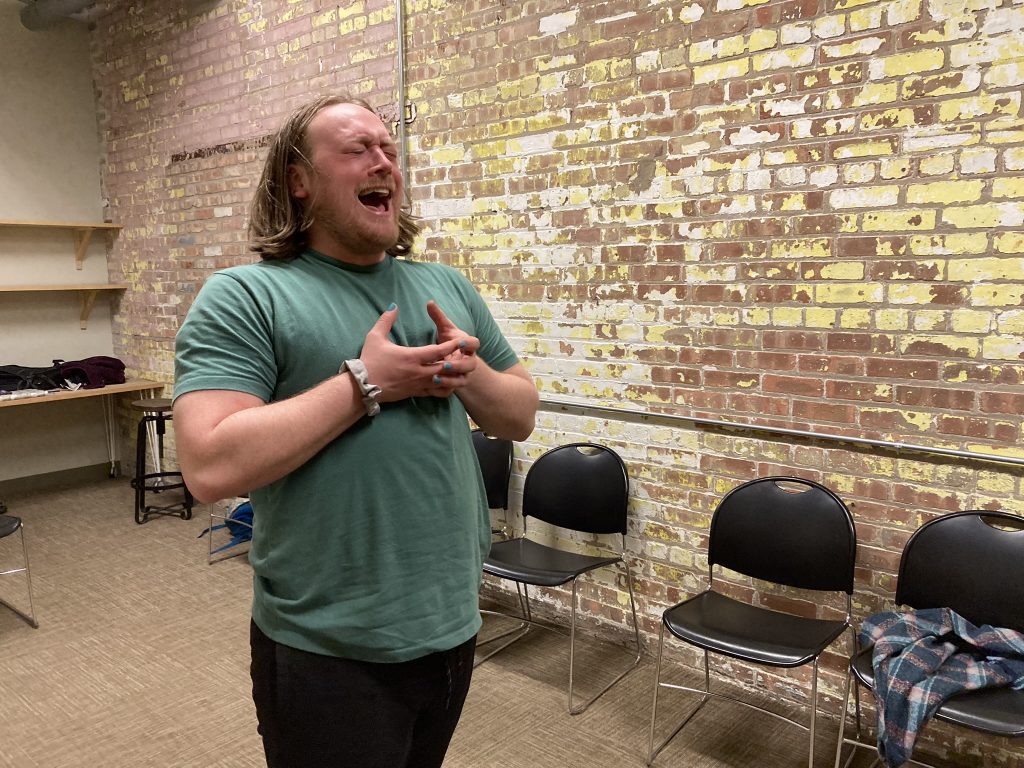 A performer is holding his hands to his chest while crying.